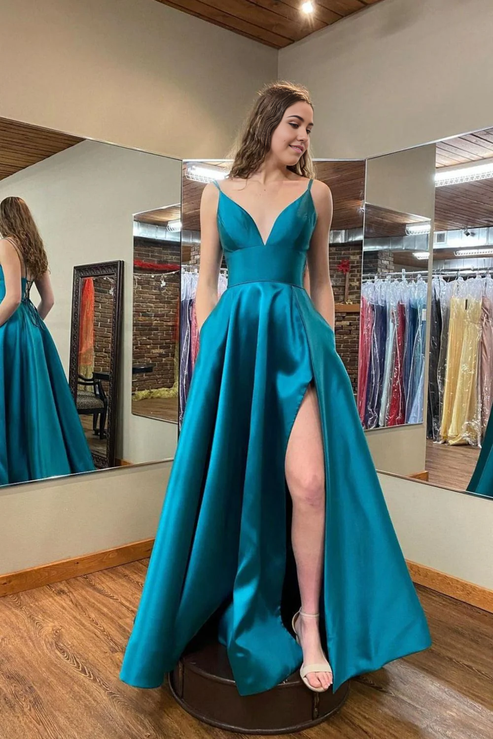 Woman wearing a green A-line V-neck long prom dress with a high slit.