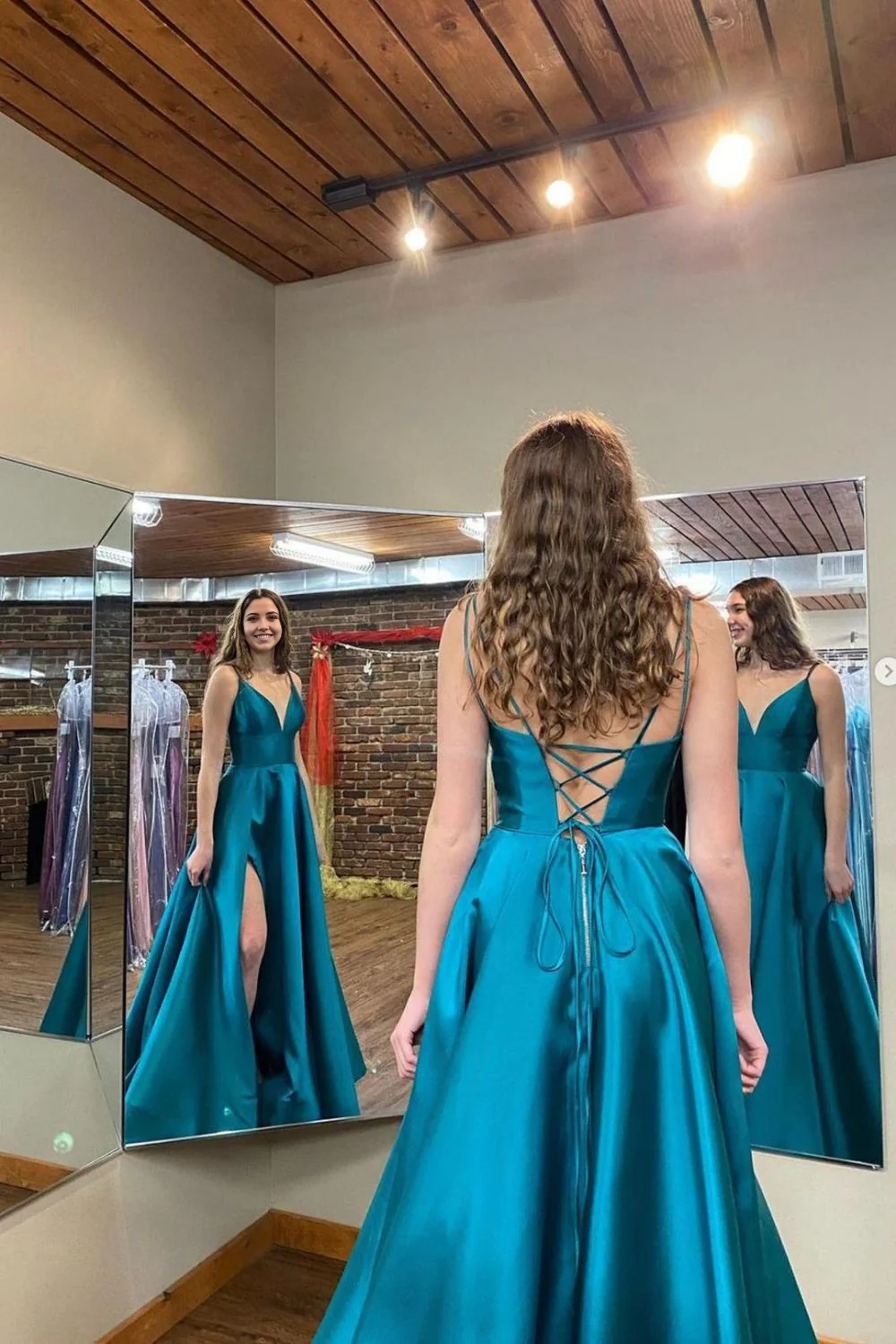 Back view of a woman in a green A-line V-neck evening gown.