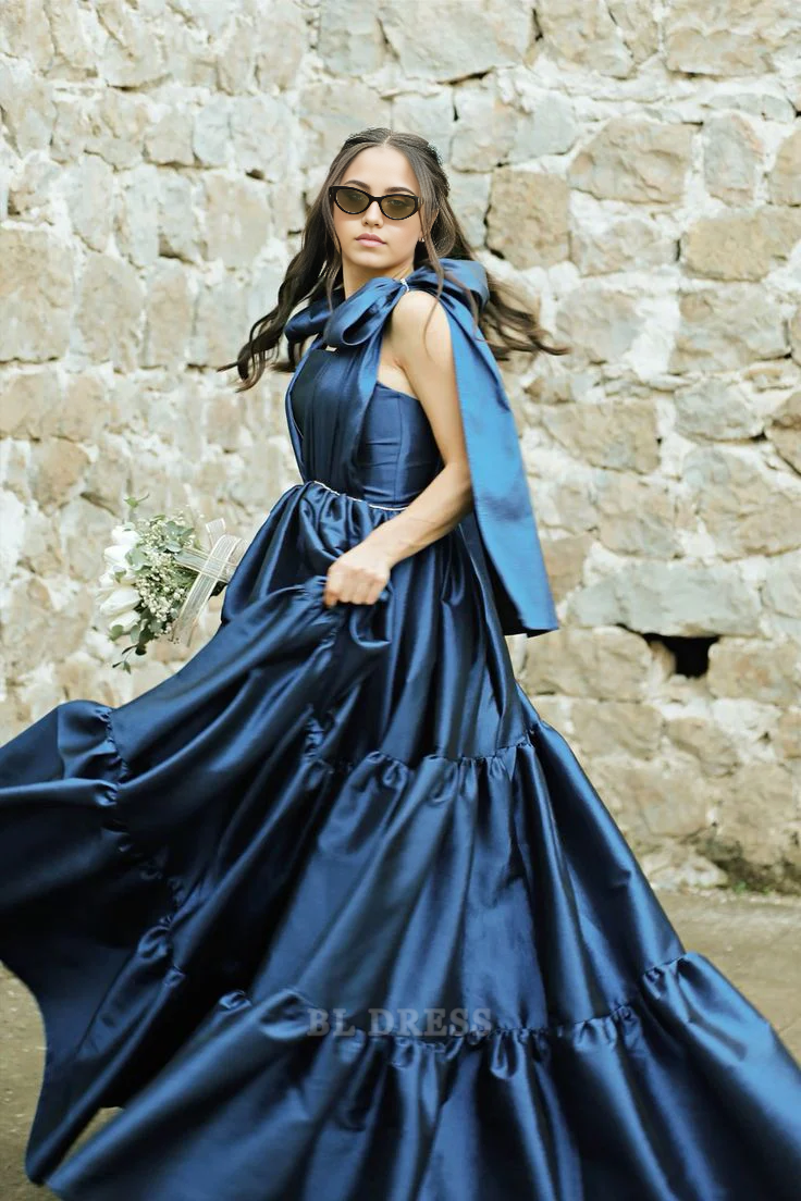 Model wearing an elegant navy blue A-line satin formal dress with V-neck and spaghetti straps.