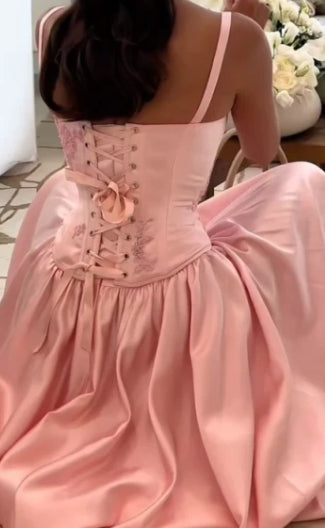 Full length view of a woman wearing the pink satin A-line dress.