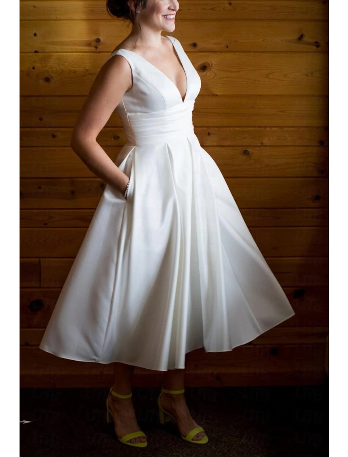 Close-up of the ruched bodice and V-neckline on the white satin wedding dress.