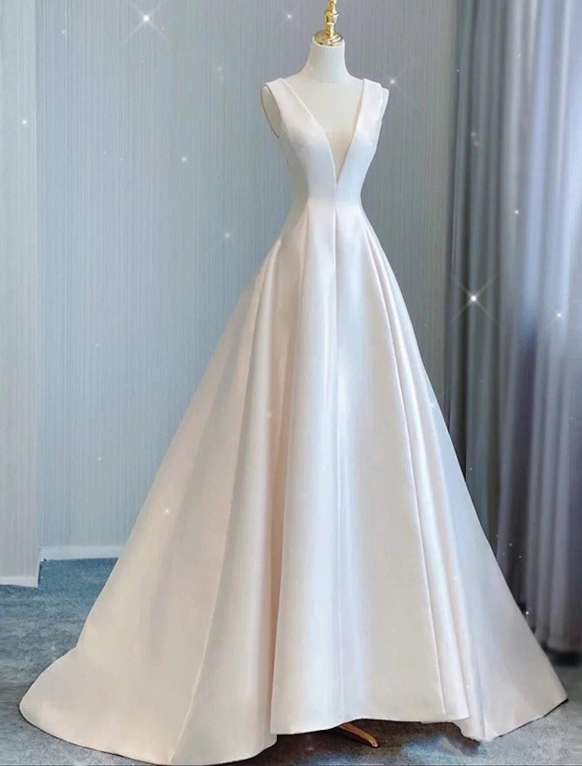 Back view of a sleeveless satin bridal gown with pleats and a flowing train.