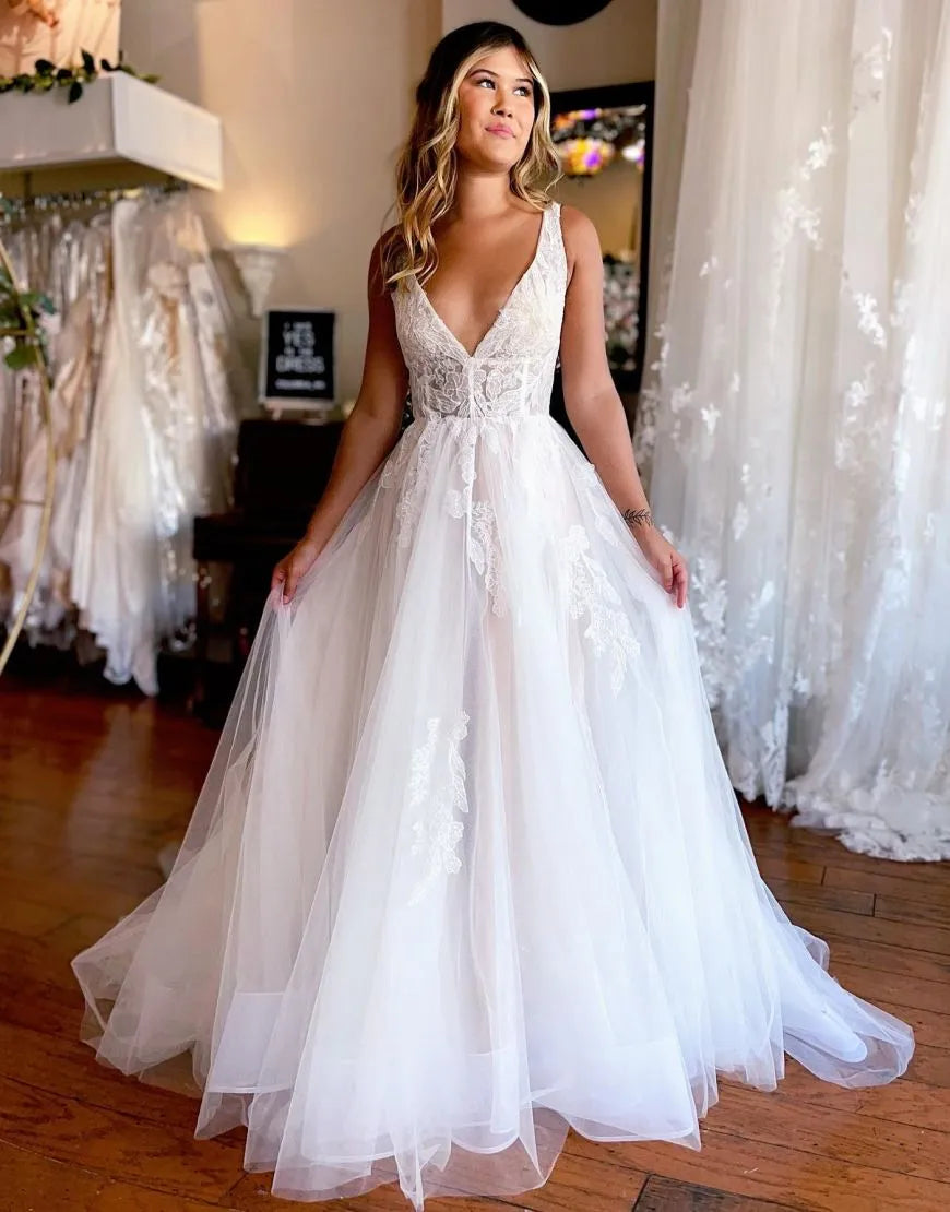 Model wearing an A-line V-neck wedding dress with appliques and a chapel train.