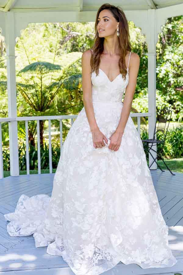 Elegant A-line lace wedding dress with spaghetti straps and backless design.