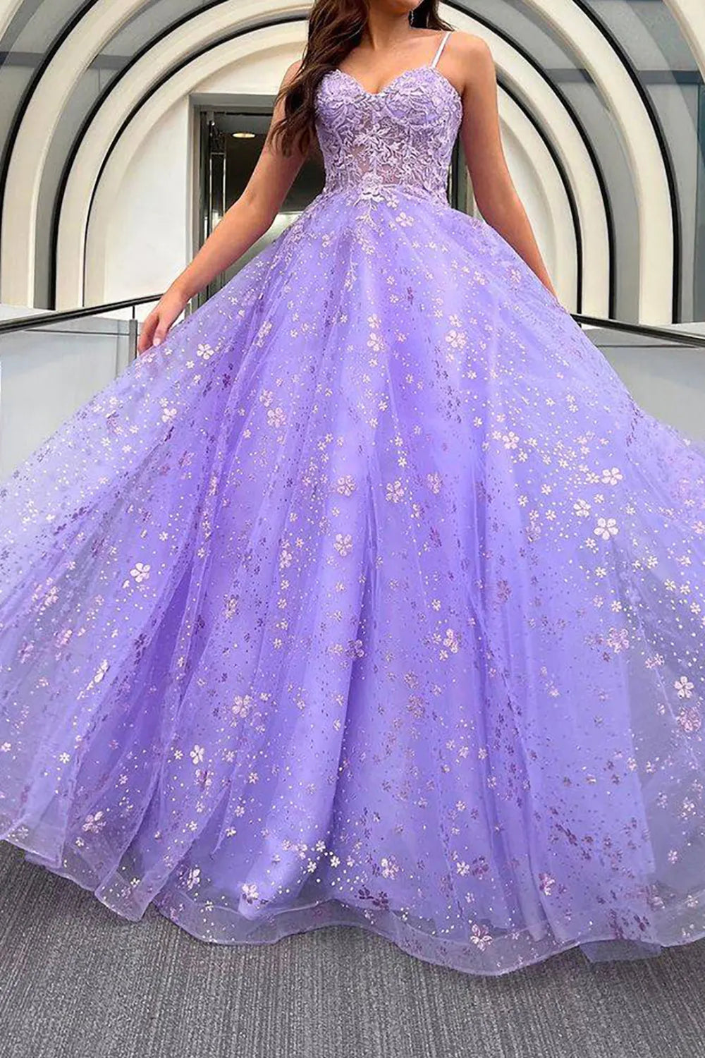 Woman wearing an elegant A-line spaghetti strap prom dress with intricate appliques.
