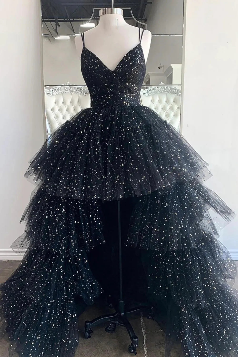 Model wearing an elegant high-low prom dress with spaghetti straps and ruffles.