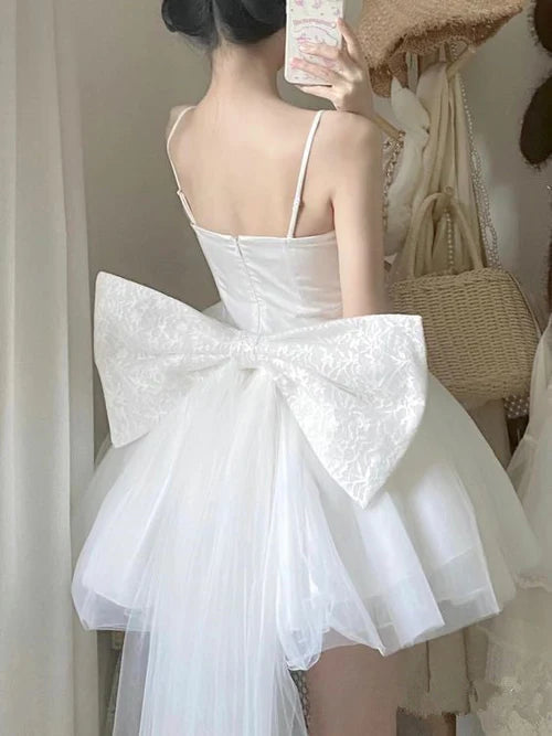 Model wearing a short white A-line dress with spaghetti straps.
