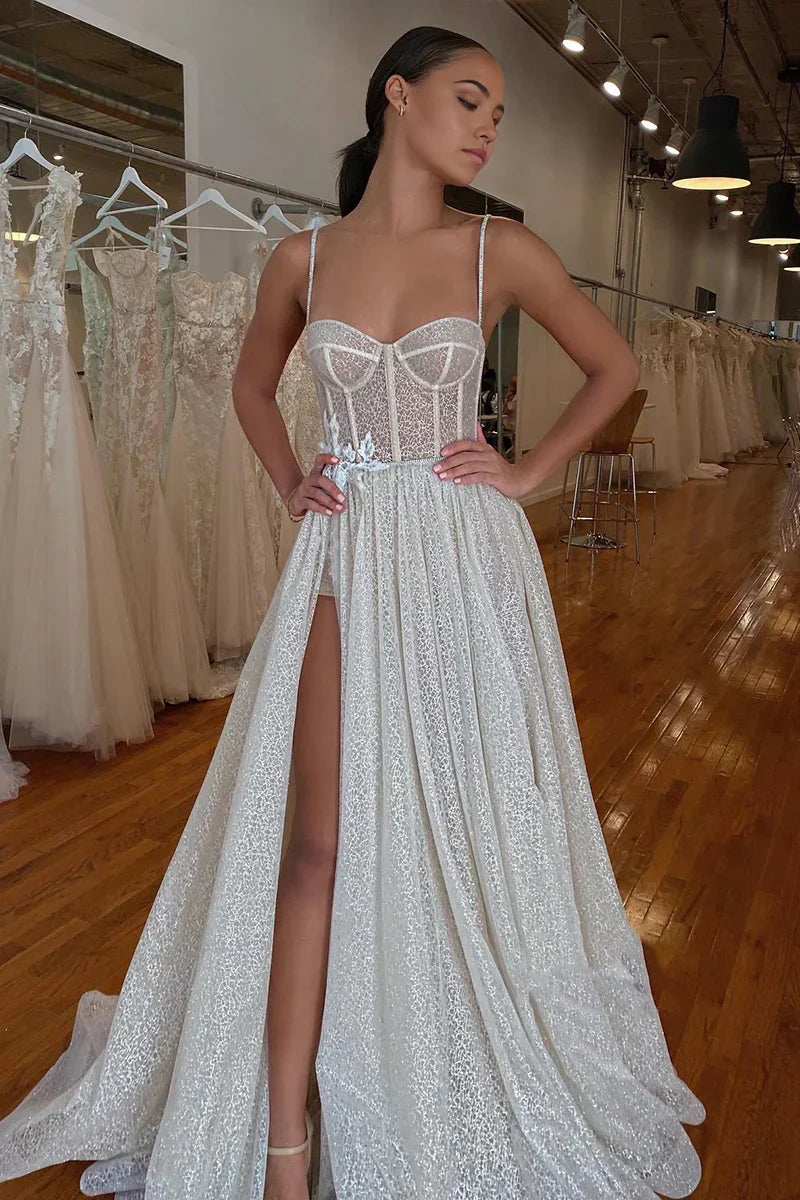 A-line wedding dress with spaghetti straps, V-neck, lace appliques, and sparkling details.