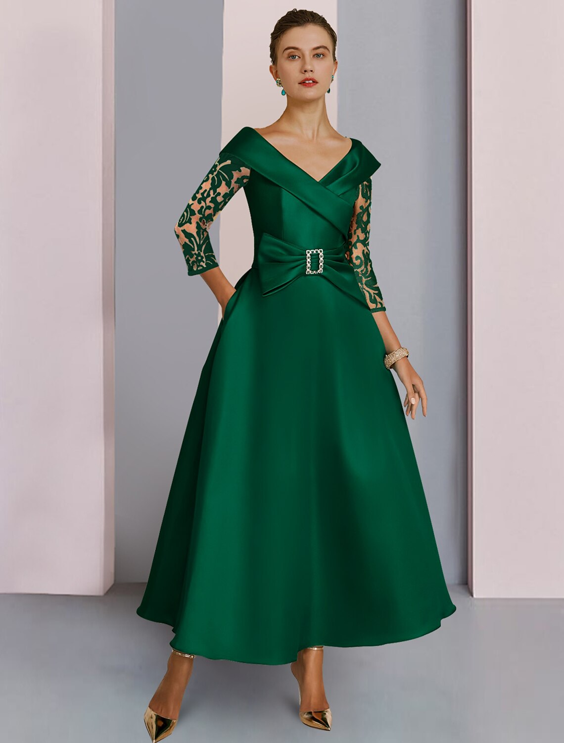 Elegant A-Line V-neck tea length dress with 3/4 sleeves, sequined lace, and a crystal brooch detail.