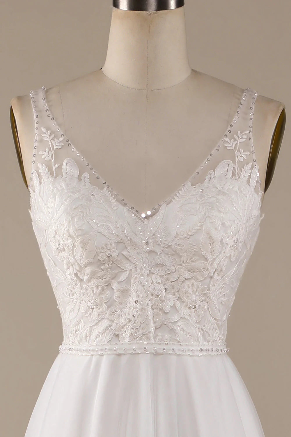 Close-up of the lace detailing on the bodice of an ivory V-neck wedding dress.