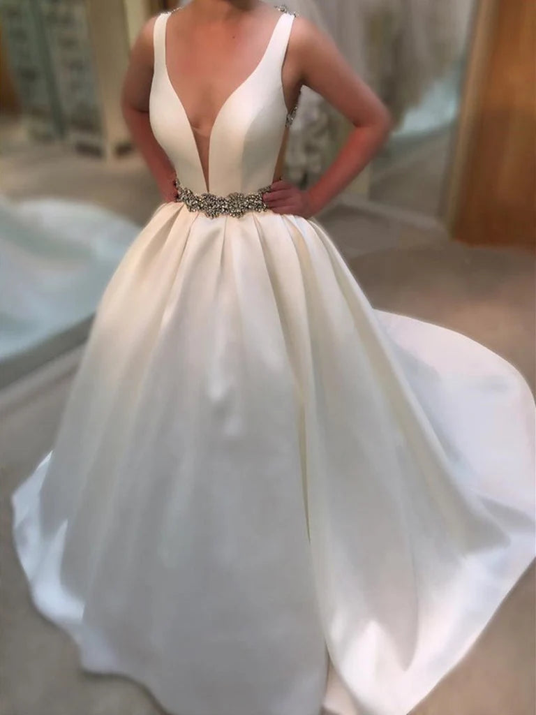 Model wearing an elegant A-line deep V-neck backless satin wedding dress with beading and a sweep train.
