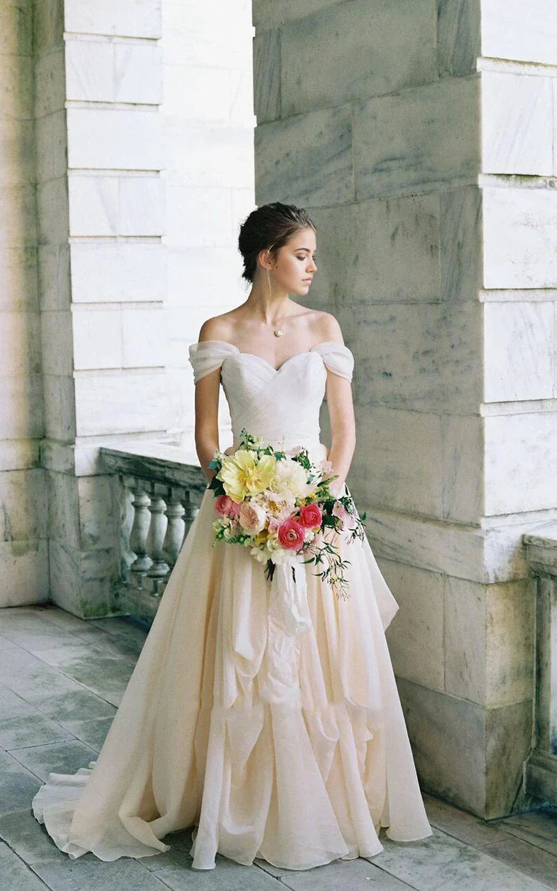 Elegant A-line off-shoulder wedding dress with draped details and criss-cross back.