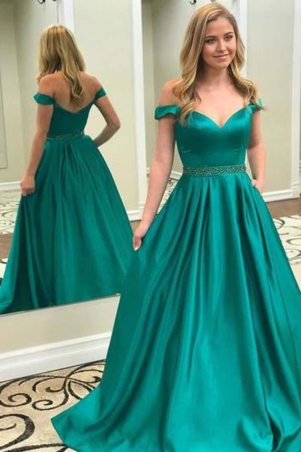 Woman wearing an elegant emerald green A-line off-shoulder long prom dress.