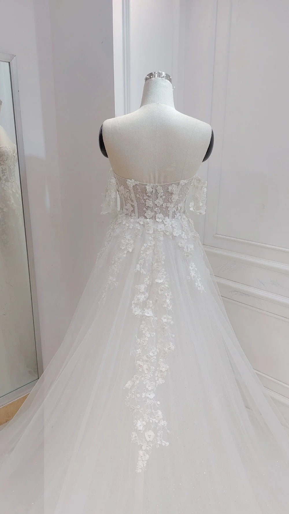 Full view of A-line off-shoulder wedding dress with intricate flower details.