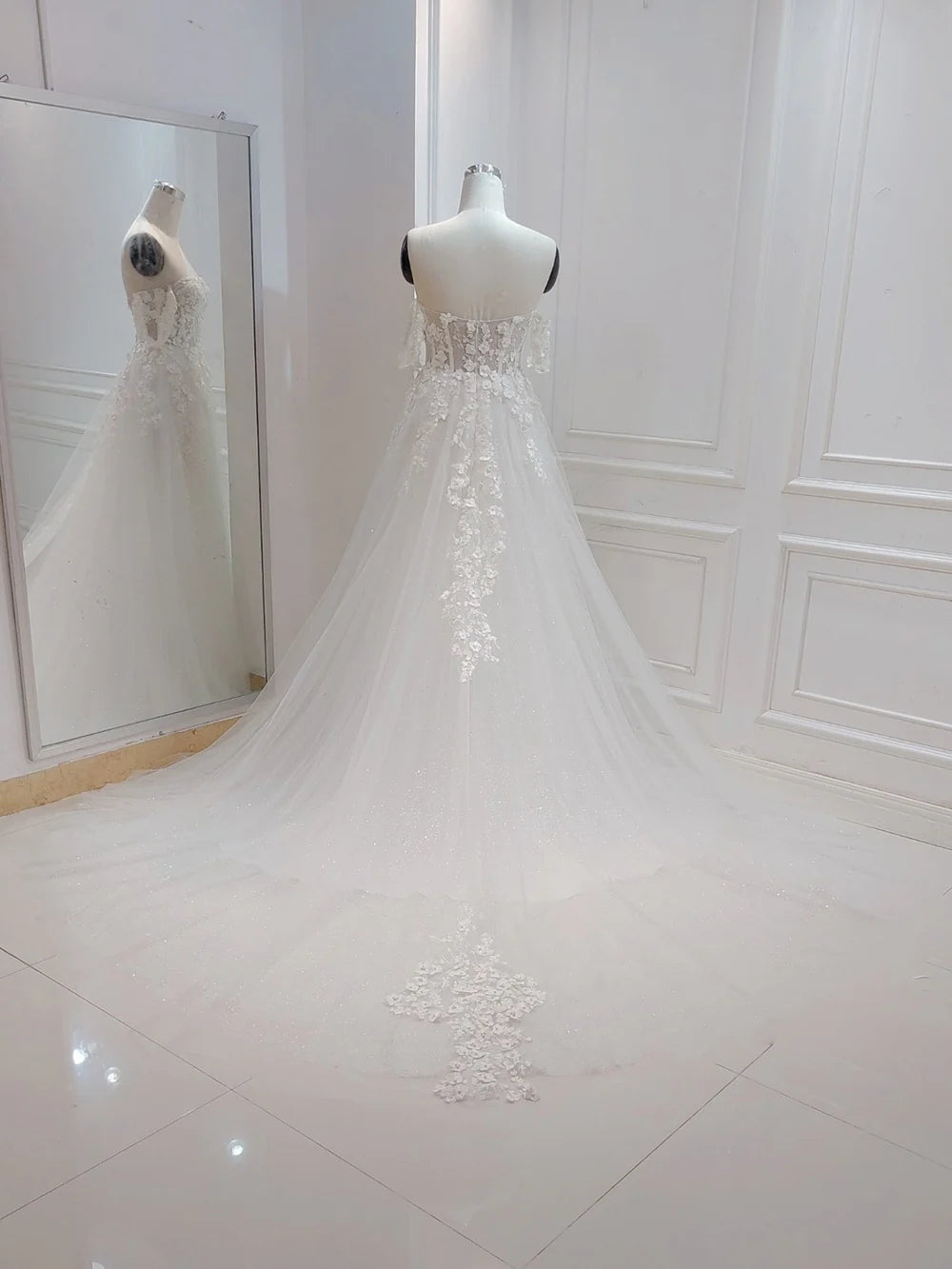 Close-up of flower embroidery on white A-line wedding gown.