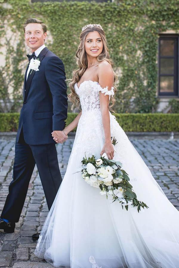 Elegant A-line off-shoulder wedding dress with lace appliques and tulle skirt.