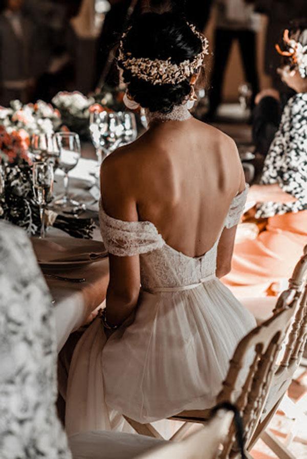 Side profile of a bride wearing an ivory A-line off-shoulder wedding dress with lace details.