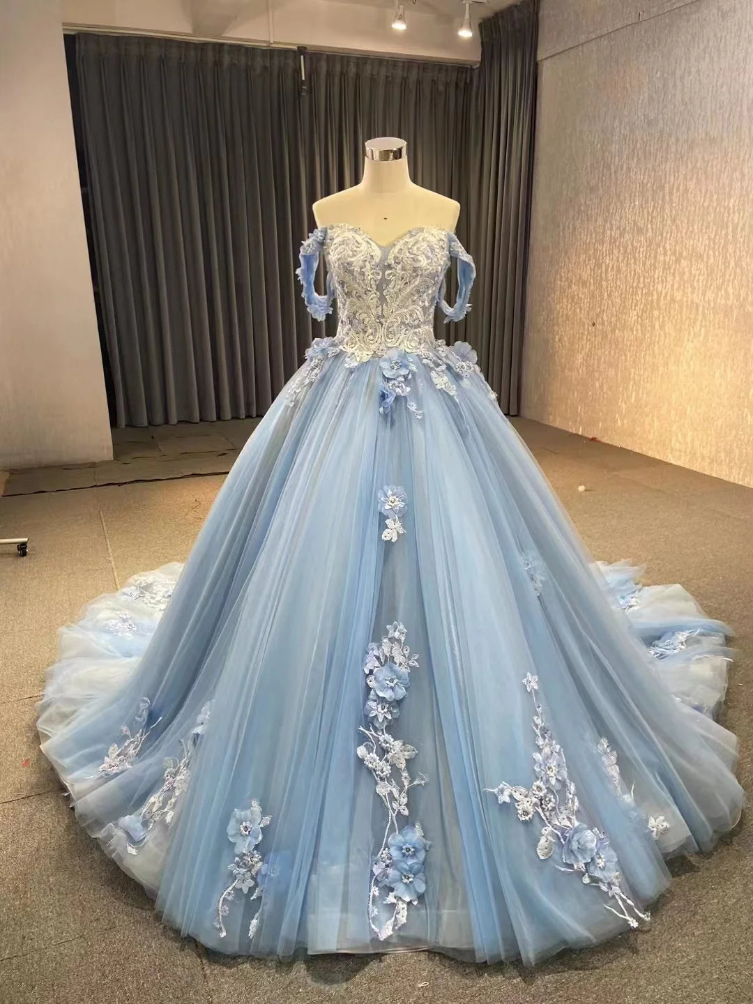 Elegant blue A-line off-shoulder ball gown with lace bodice and tulle skirt.