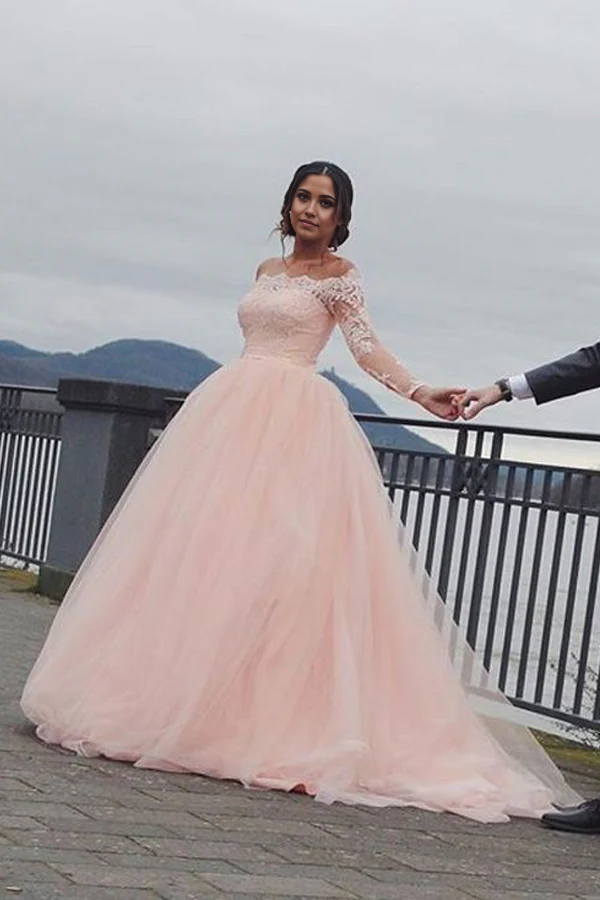 Model wearing an elegant A-line off-shoulder blush pink wedding dress with long sleeves.
