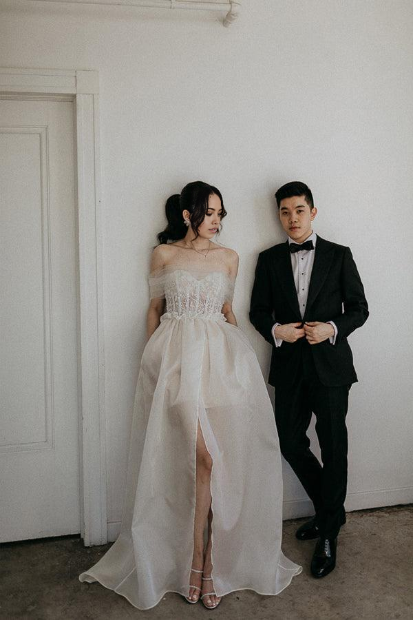 Model in elegant A-line off-shoulder satin wedding dress with lace detail.