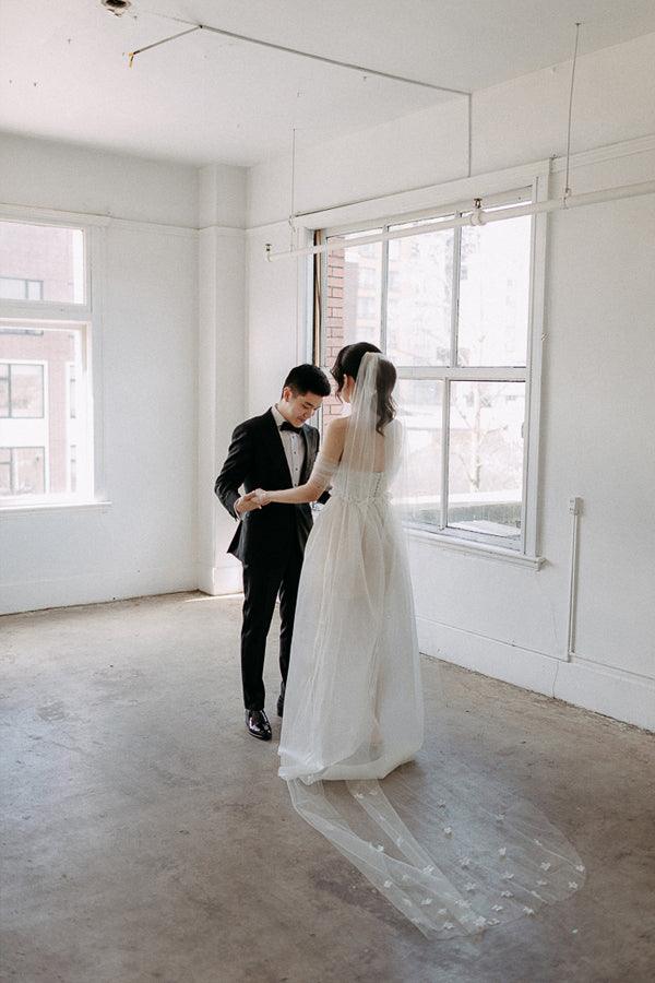 Back view of the A-line off-shoulder satin wedding dress with flowing train.