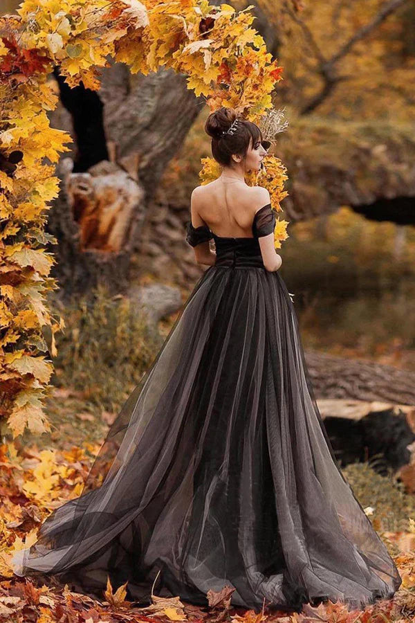Full view of a simple black A-line wedding gown featuring an off-shoulder neckline and long skirt.