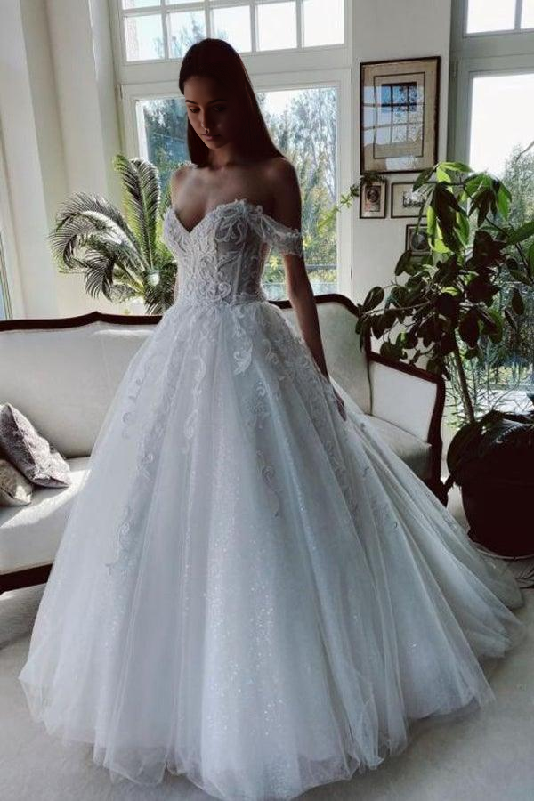 Close-up of off-shoulder neckline and beaded appliques on a white wedding gown.