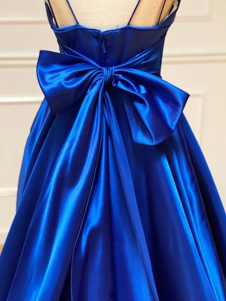 Close-up of the bowknot detail on a royal blue satin dress.