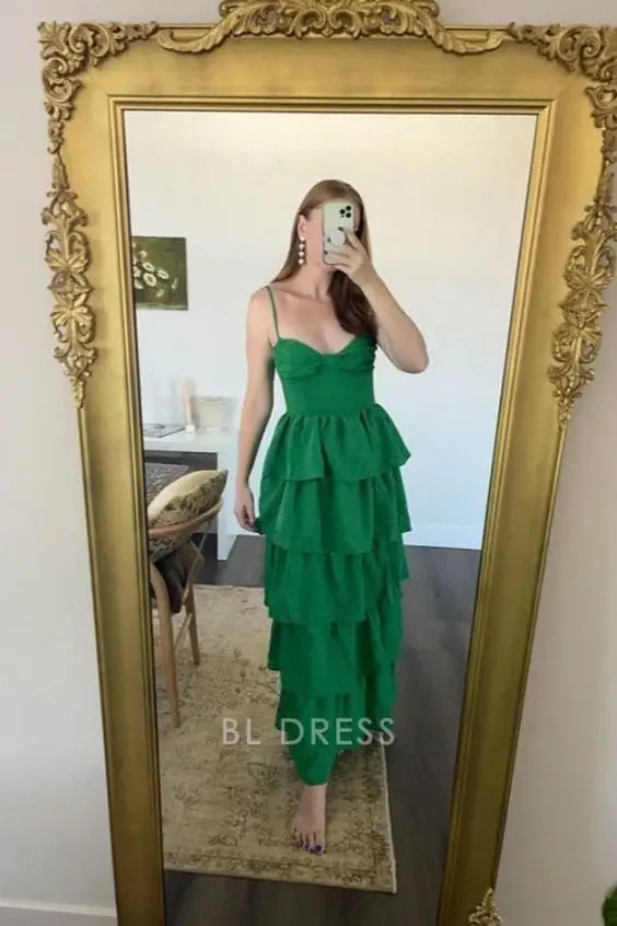 Elegant green A-line formal dress with spaghetti straps and tiered skirt.