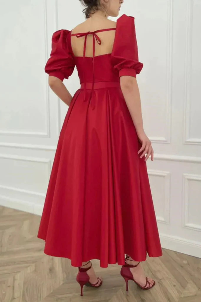 Close-up of the satin A-line dress, showing puff sleeves and square neckline details.
