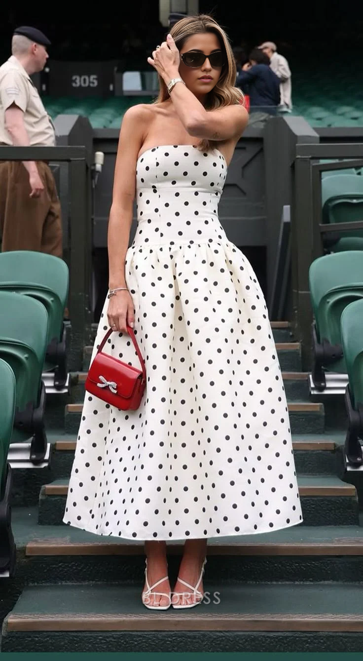 Woman wearing a black strapless A-line polka dot maxi dress.