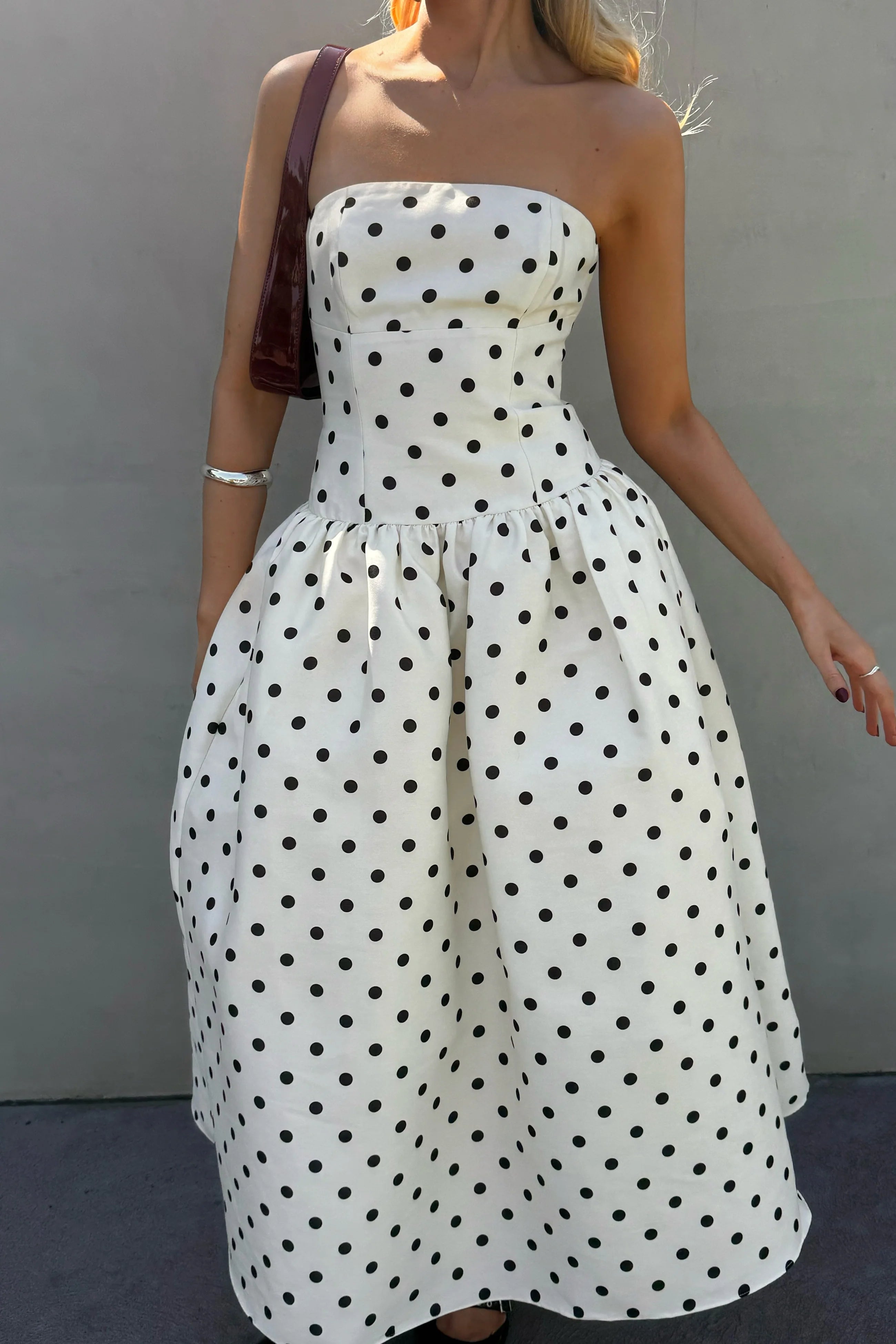 Close-up of the bodice and upper skirt of the black strapless polka dot A-line dress.