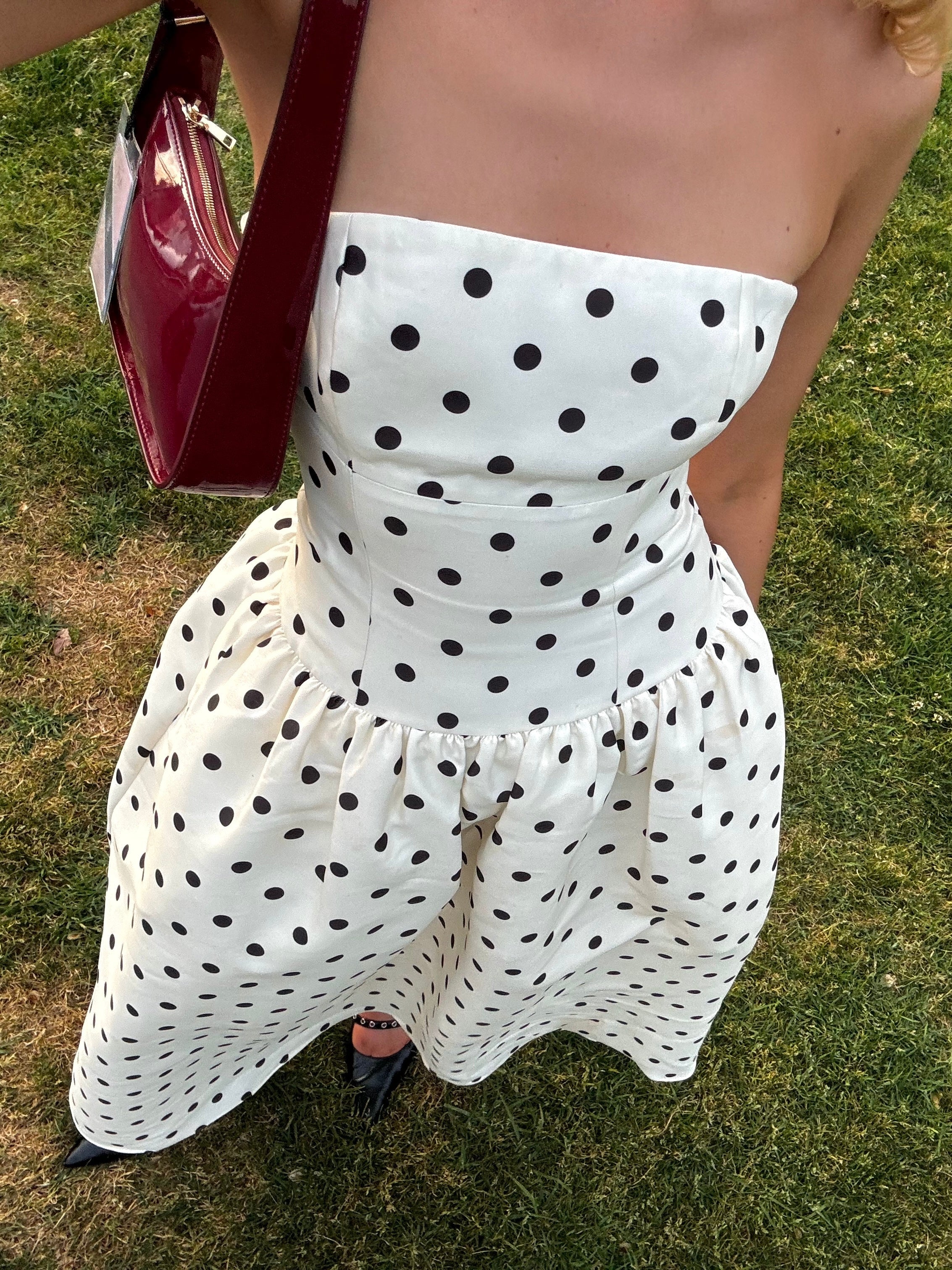 Side view of the black strapless A-line polka dot maxi dress, showing the flowing skirt.