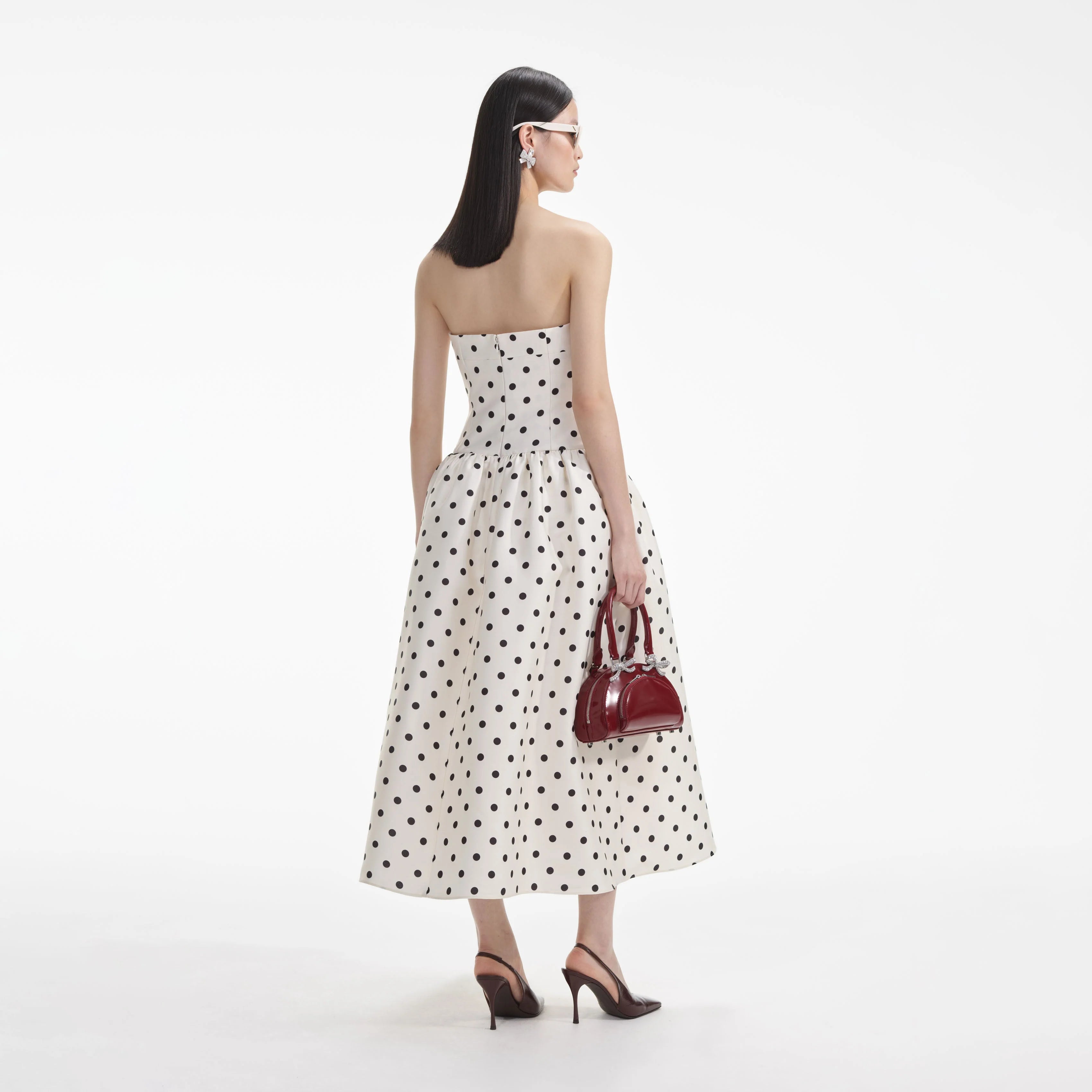 Back view of the black strapless A-line polka dot maxi dress.