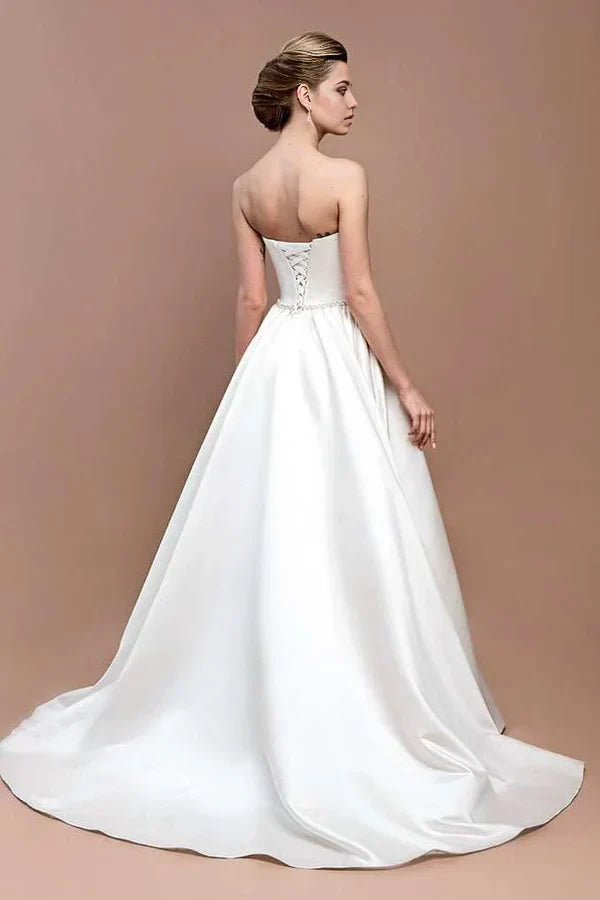 Side view of a bride wearing an elegant strapless satin wedding gown.