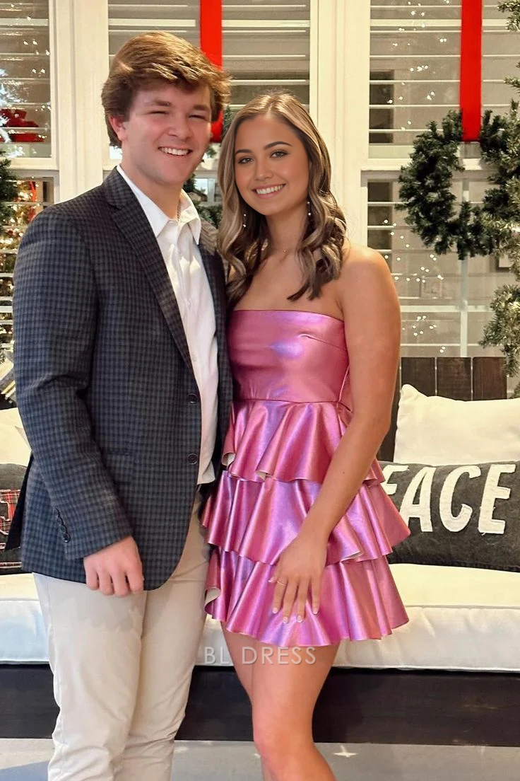 Model wearing a pink A-line strapless tiered short formal dress.