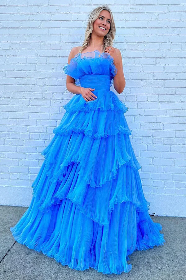 Woman wearing a blue A-line strapless tulle prom dress with ruffles.