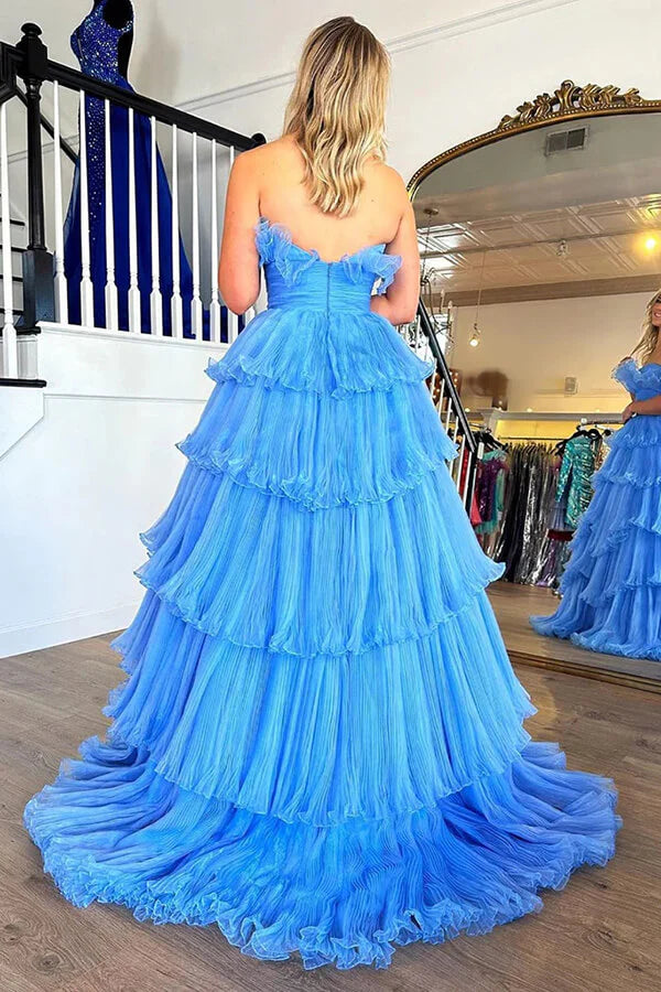 Side view of a woman in a blue strapless A-line ruffled tulle gown.