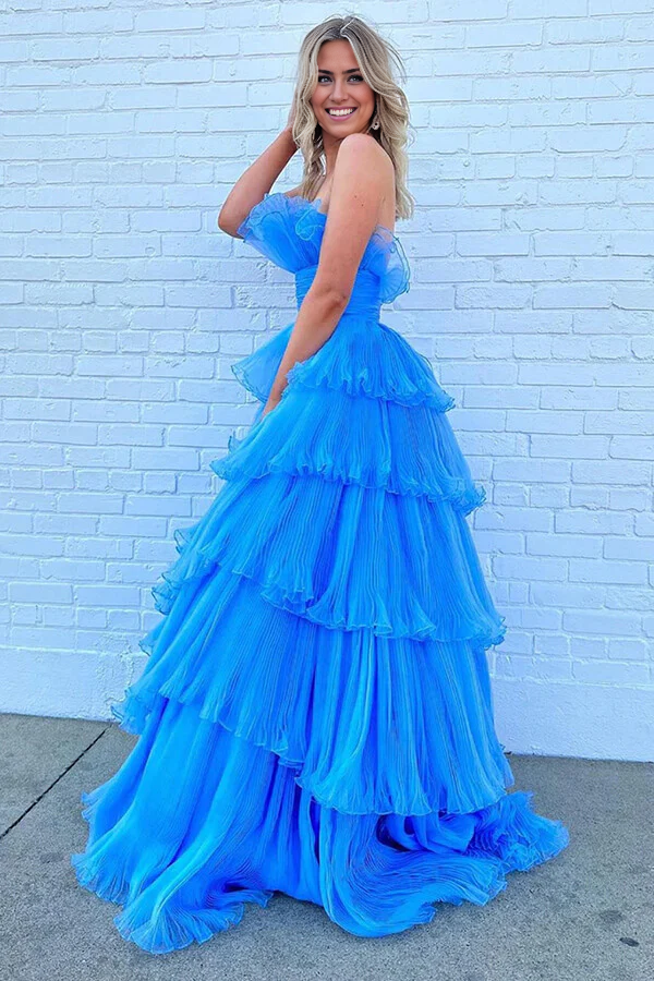 Woman posing in a blue strapless A-line prom dress with flowing ruffles.