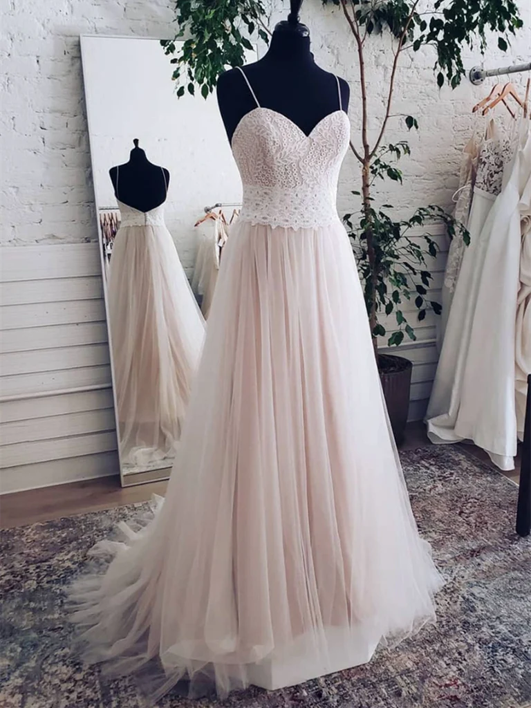 Woman wearing an elegant A-line sweetheart backless long prom dress with lace bodice and tulle skirt.
