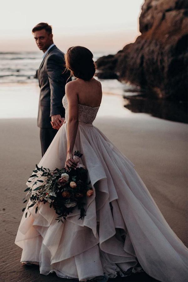 Side view of a white A-line bridal gown featuring a sweetheart neckline and intricate beading.