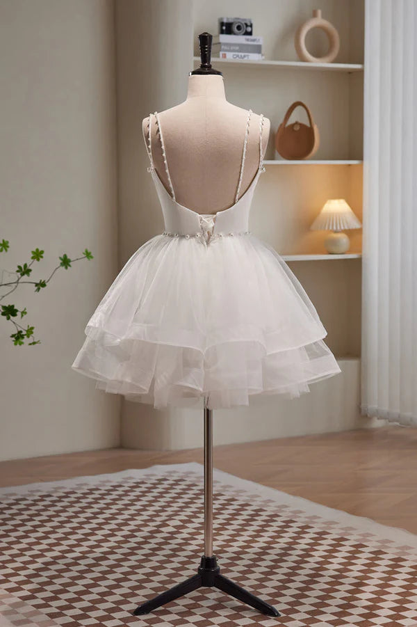 Back view of a short A-line tulle dress with delicate spaghetti straps in blush pink.