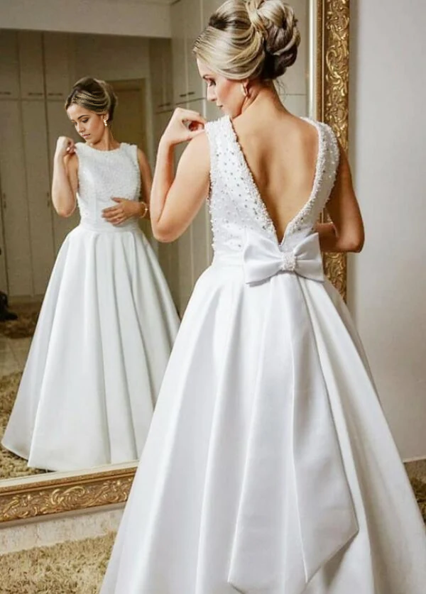 Full-length A-line wedding dress with V-neck, beaded bodice, and large back bow.