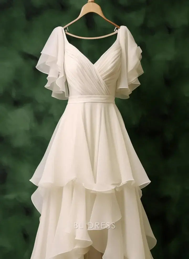 Side view of white chiffon formal dress with V-neck and flowing high-low skirt.