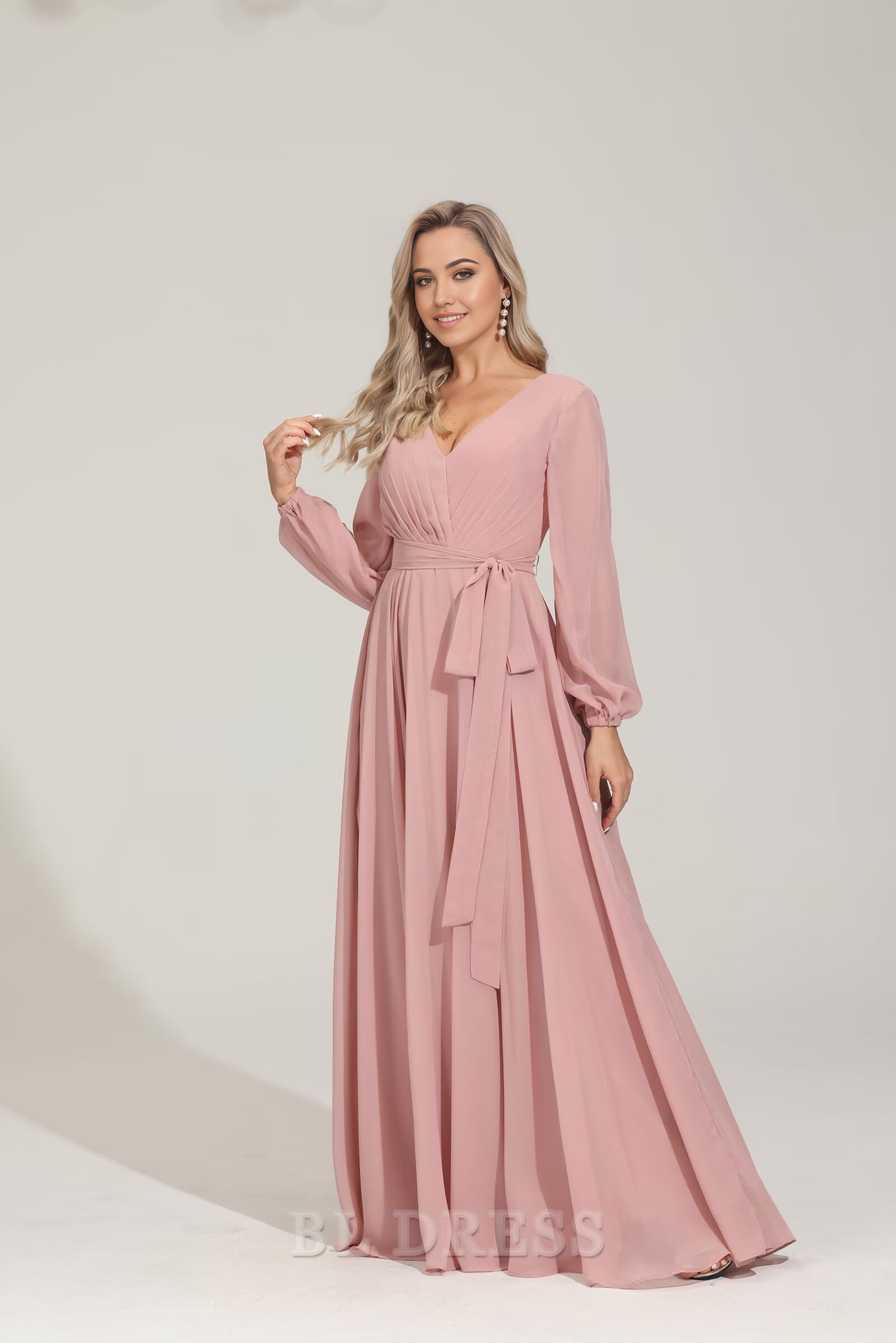 Side view of a woman in a flowy A-line V-neck long sleeve chiffon gown.