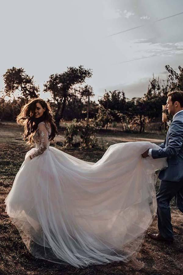 Elegant A-line V-neck long sleeve wedding dress with lace appliques and a flowing tulle skirt.
