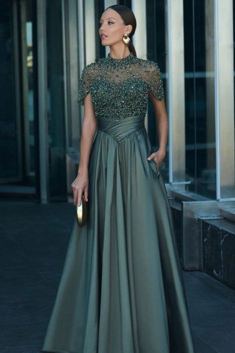 Model wearing a dark green satin A-line evening dress with short sleeves and beadings.