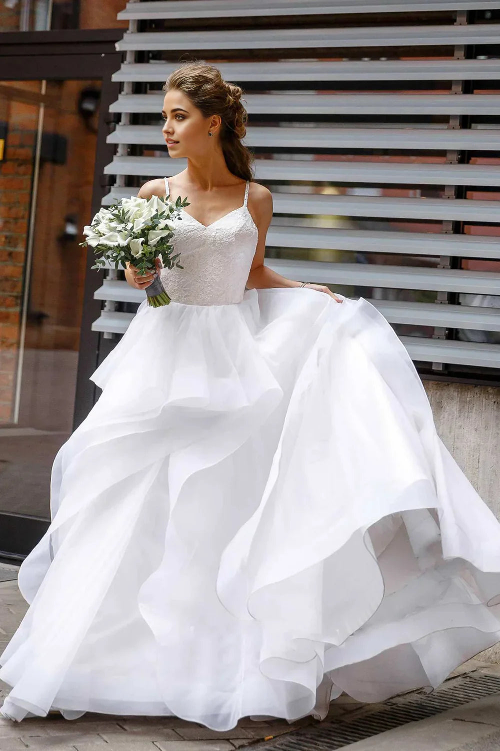 Elegant A-line wedding dress with spaghetti straps and lace top.