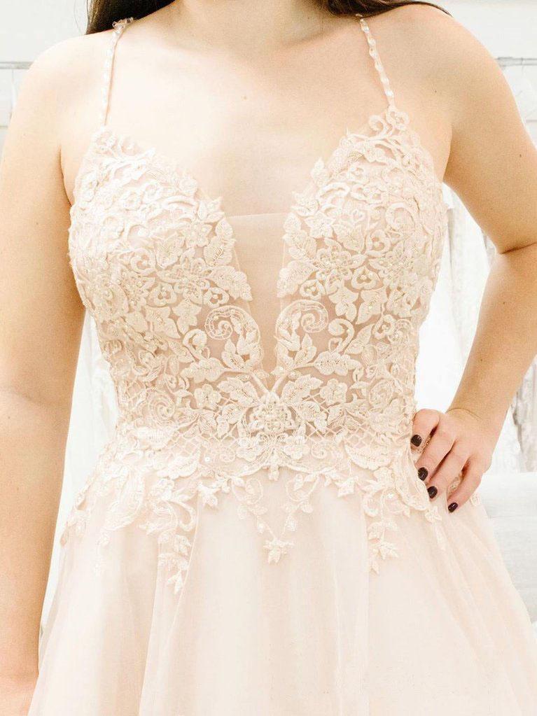 Close-up of the illusion plunging V-neckline and spaghetti straps on a wedding dress.