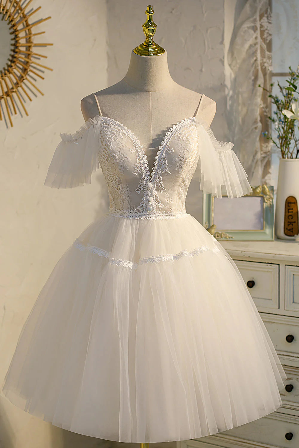 Model wearing a light pink A-line V-neck tulle homecoming dress with spaghetti straps.